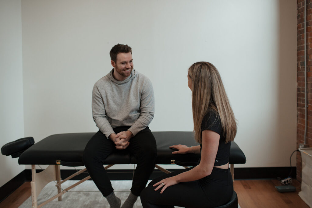 Dr. Brooke talking to male patient on physical therapy table
